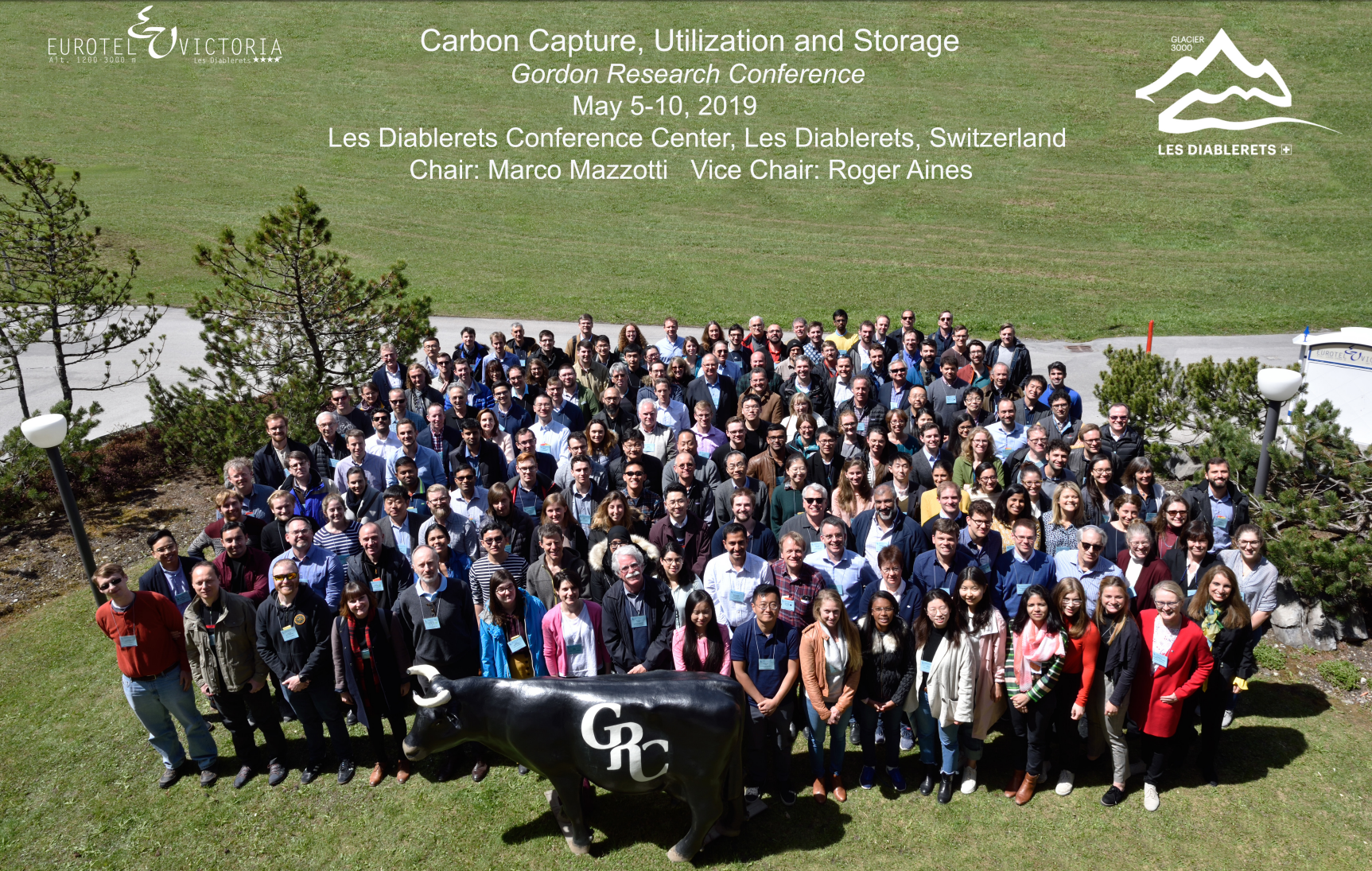 Approximately 200 of the conference attendees stand in a grassy field in Switzerland